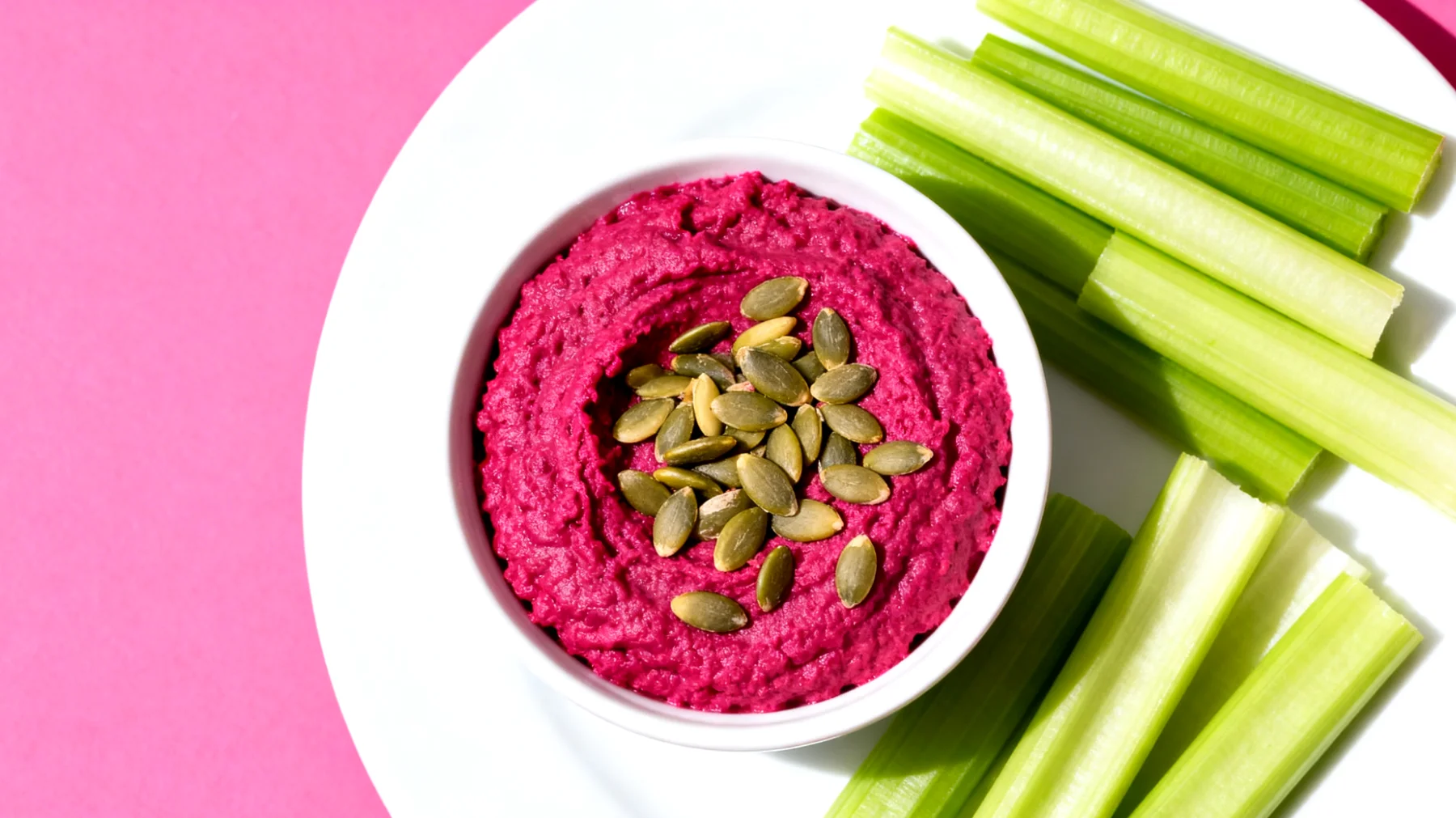 Rote-Bete-Hummus mit Selleriestangen und Kürbiskernen"